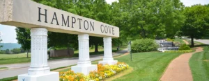 Hampton Cove entrance sign with white columns, flower beds, and a landscaped waterfall.